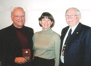  Steve Dunn, President of the Hamilton Serra Club presents a plaque to Paul and Sherry Wendling in recognition of their son Mark's ordination.